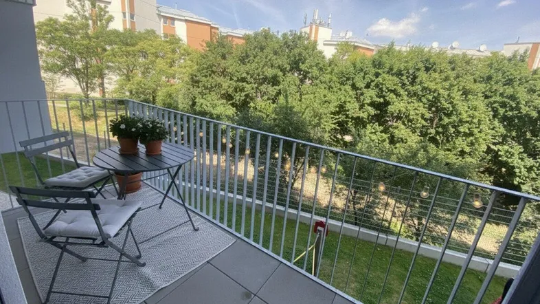 Möblierter Balkon mit Fliesenboden und Blick ins Grüne, ideal für entspannte Stunden im Freien.