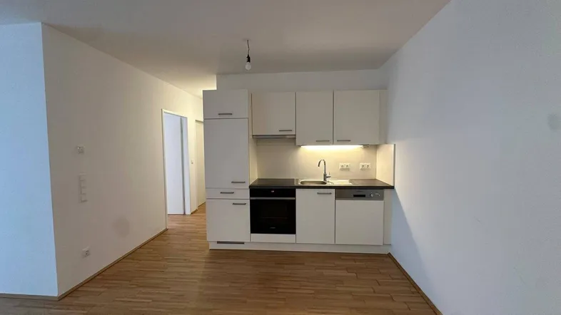Helle Wohnküche mit moderner Einbauküche, Parkettboden und integrierten Geräten.