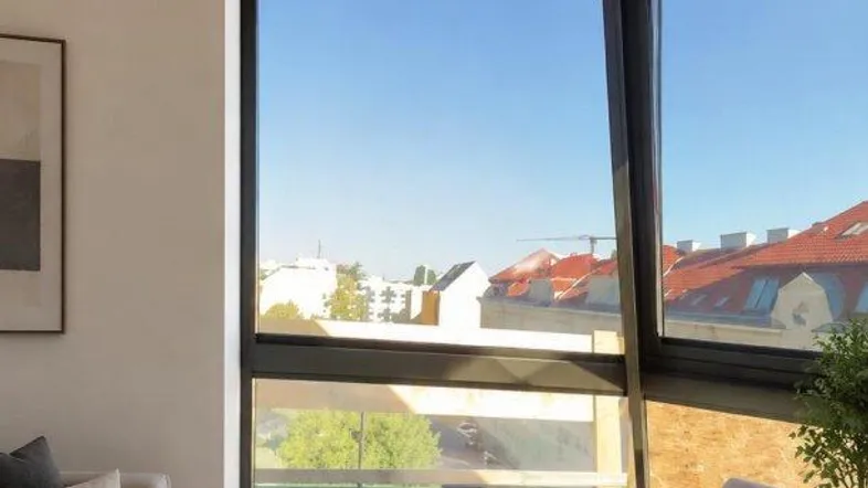 Helles Wohnzimmer mit großen Eckfenstern, die einen weiten Blick über die Stadt bieten.