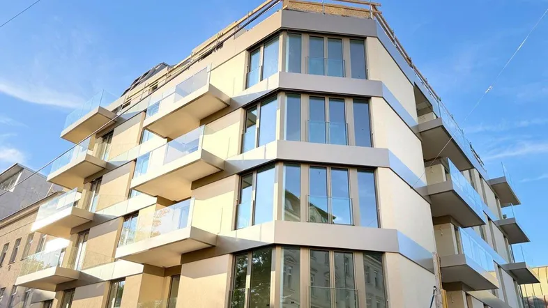 Eckansicht eines modernen Wohnhauses mit vielen Balkonen und großen Glasflächen.