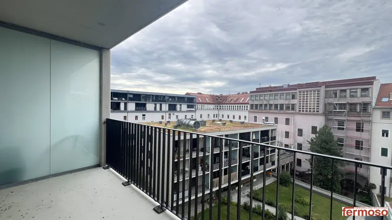 Geräumiger Balkon mit Blick auf den Innenhof und umliegende Gebäude, ideal für entspannte Stunden im Freien.