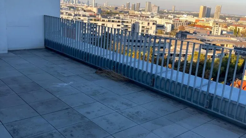 Große Dachterrasse mit Fliesenboden und weitem Blick über die Stadtkulisse.