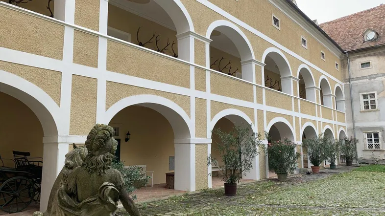 Historischer Innenhof mit Arkadengängen und dekorativen Geweihen an den Wänden.