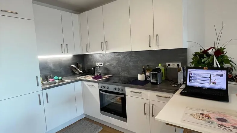 Moderne Küche mit weißen Schränken, Holzboden und integrierten Geräten, ideal für den täglichen Gebrauch.
