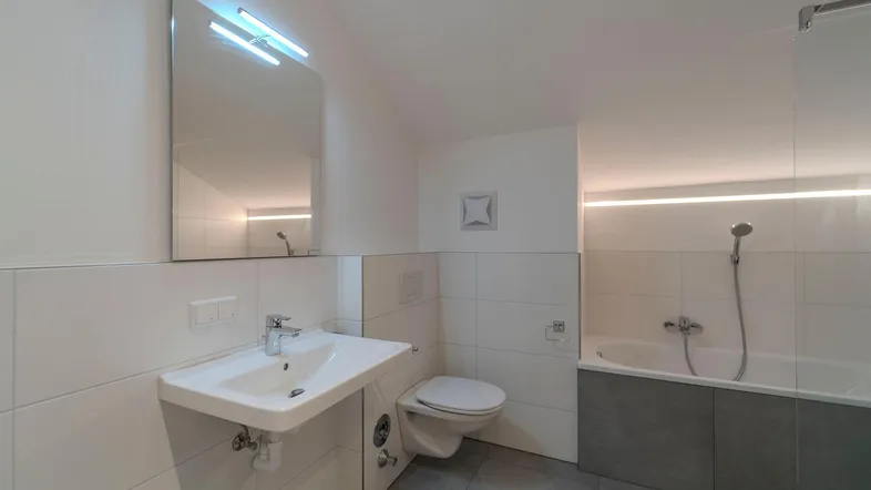Modernes Badezimmer mit Waschbecken, Toilette, Badewanne und indirekter LED-Beleuchtung.