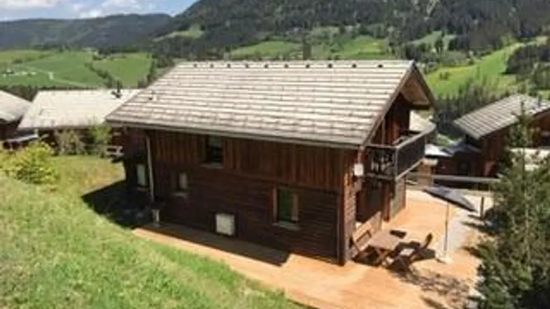 Ein charmantes Holzhaus in alpiner Umgebung mit Satteldach und einer kleinen Terrasse.