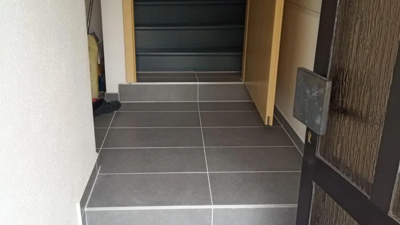 Eingangsbereich mit modernen grauen Fliesen und Treppenaufgang in die obere Etage.