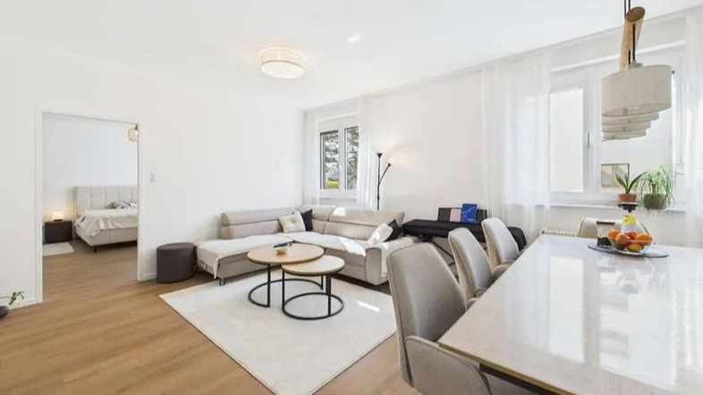Helles und offenes Wohn-Esszimmer mit modernem Sofa, Esstisch und Parkettboden.