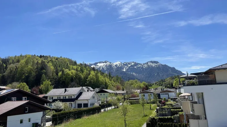Panoramablick auf die umliegende Berglandschaft und die Wohnsiedlung unter blauem Himmel.