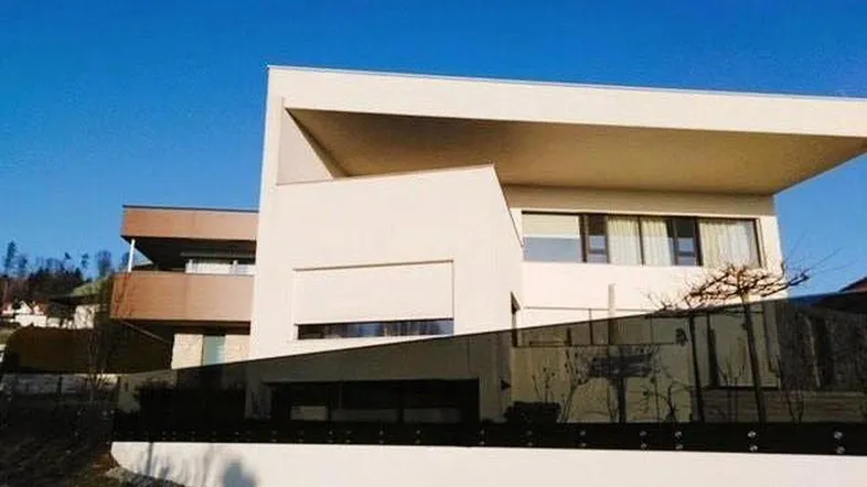 Moderne Architektur mit klaren Linien und weißer Fassade unter blauem Himmel.
