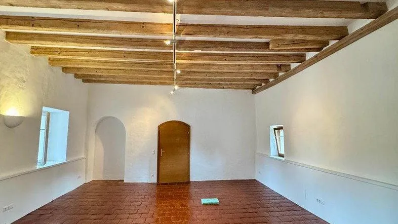 Geräumiger Innenraum mit sichtbaren Holzbalken an der Decke und traditionellem Terrakottaboden.