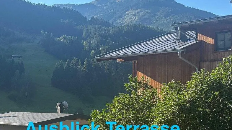 Panoramablick auf die umliegende Berglandschaft mit bewaldeten Hängen und einem traditionellen Gebäude.