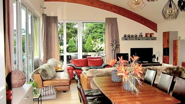 Geräumiger Wohn-Essbereich mit hohen Decken, Holzbalken und Zugang zur Terrasse.