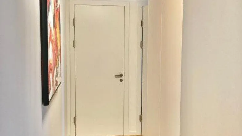 Heller Flur mit hellem Holzfußboden, weiß gestrichenen Wänden und integrierten Schränken.
