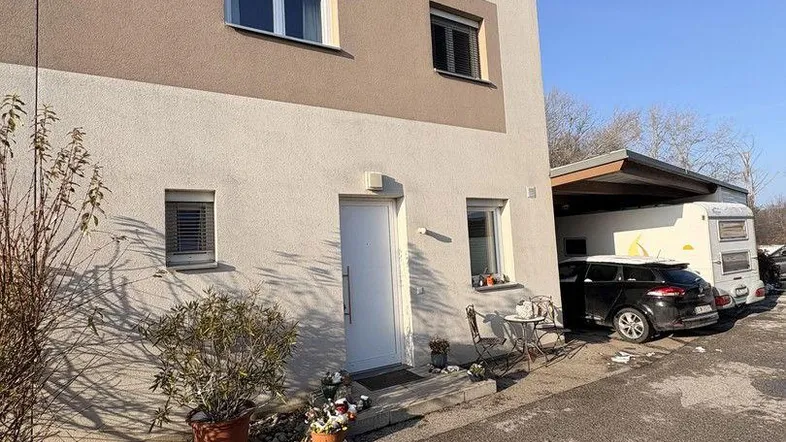 Modernes Einfamilienhaus mit heller Fassade und Carport, teilweise mit Schnee bedeckt.
