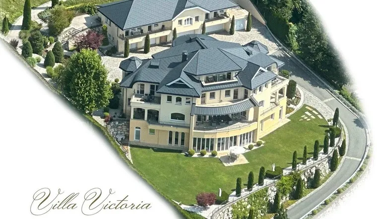 Luftaufnahme einer luxuriösen Villa mit Nebengebäude, umgeben von gepflegten Gärten und Zufahrten.