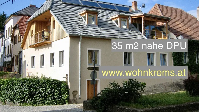 Mehrfamilienhaus mit Solarpaneelen auf dem Dach und Balkonen in einer städtischen Umgebung.