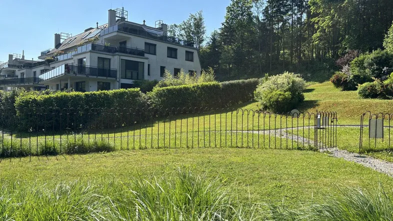 Moderne Wohnanlage mit Terrassen und Balkonen, umgeben von grüner Landschaft und Bäumen.