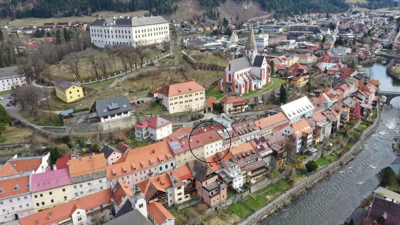 Luftaufnahme einer historischen Stadt mit Fluss, Burg und dem markierten Gebäude im Zentrum.