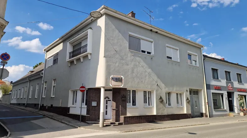 Gebäudeansicht von der Straße mit Rollläden an den Fenstern und einem kleinen Balkon.
