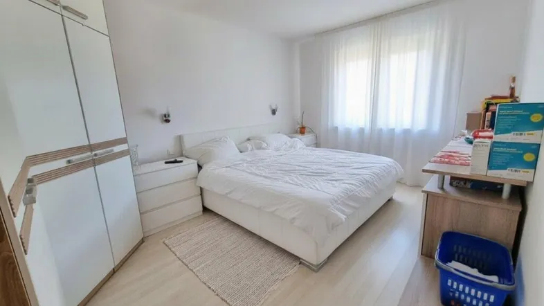 Helles Schlafzimmer mit Doppelbett, weißem Kleiderschrank und hellem Laminatboden.