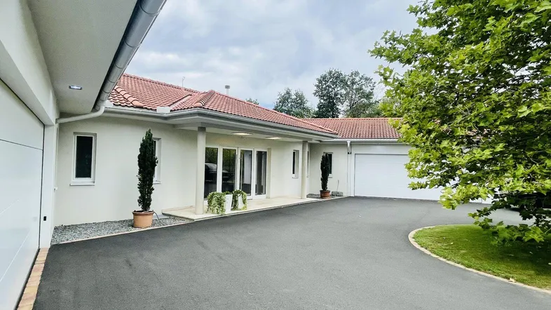Vorderansicht des Hauses mit Zufahrt, Garagen und gepflegtem Eingangsbereich.