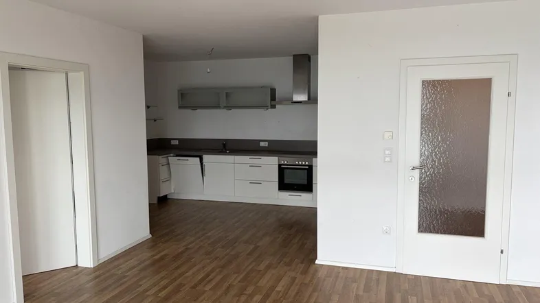 Offener Wohnbereich mit Laminatboden und Blick auf die integrierte, moderne Küchenzeile.