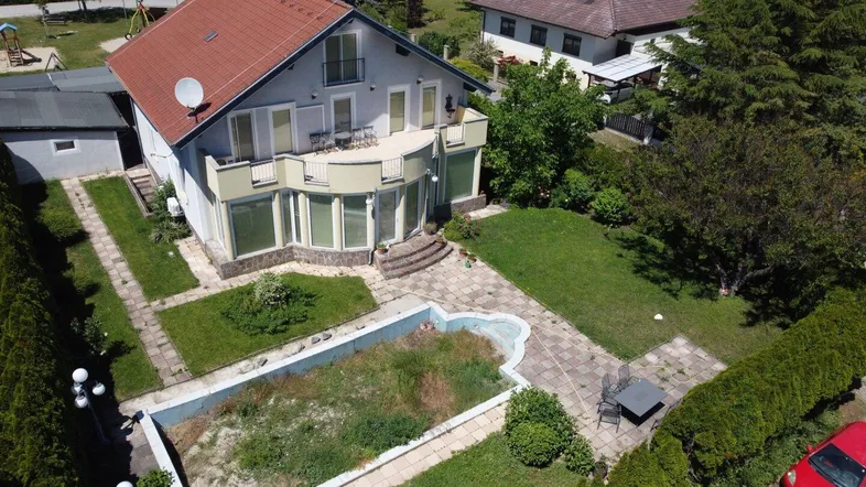 Luftaufnahme des Hauses mit großem Gartenbereich, Terrasse und einem derzeit ungenutzten Pool.
