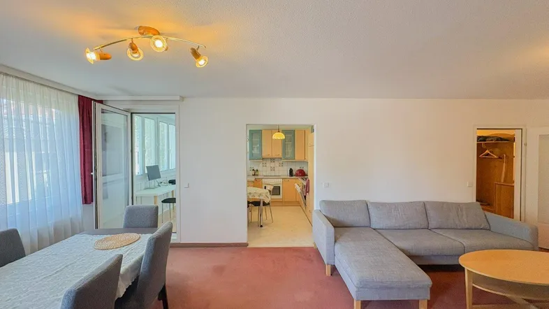 Geräumiger Wohn-Essbereich mit gemütlichem Sofa, Esstisch und Blick in die angrenzende Küche.