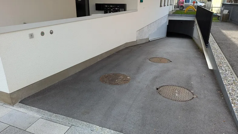Einfahrt zur Tiefgarage eines modernen Wohngebäudes mit gepflastertem Zugangsbereich.