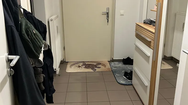 Heller Eingangsbereich mit Fliesenboden, Garderobe und Schuhablage.