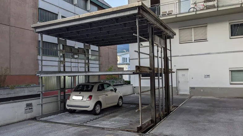 Außenansicht eines mechanischen Parksystems mit einem geparkten Auto in einer städtischen Umgebung.