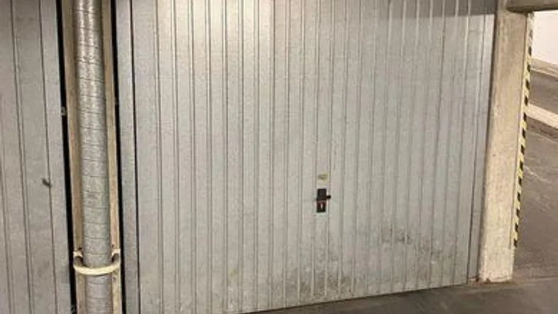 Metallgaragentor mit vertikalen Lamellen und sichtbaren Gebrauchsspuren in einer Tiefgarage.
