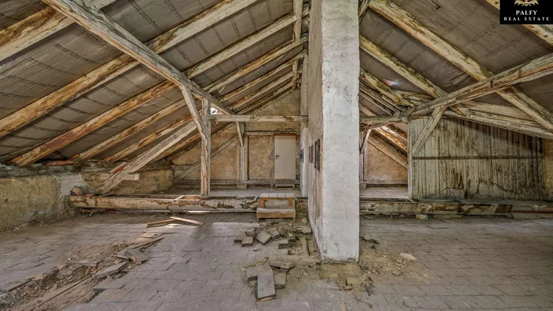 Unfertiger Dachboden mit sichtbaren Holzbalken und schrägen Dächern, bereit für den Ausbau.