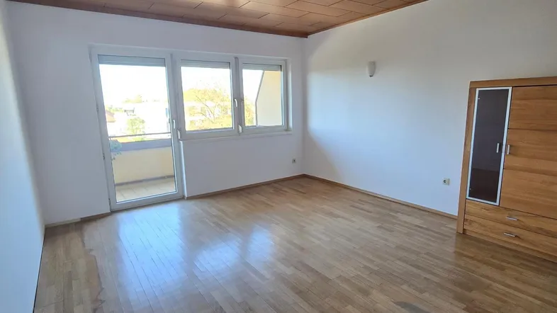 Helles Wohnzimmer mit Parkettboden, Holzdecke und direktem Zugang zum Balkon.