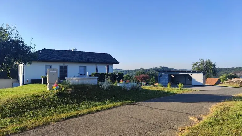 Einfamilienhaus mit Carport und weitem Blick über die grüne Landschaft in ländlicher Umgebung.