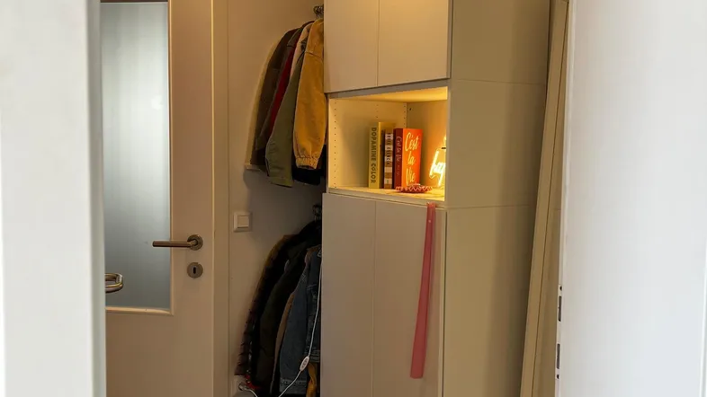 Heller Eingangsbereich mit Garderobenschrank, Spiegel und Holzboden für eine einladende Atmosphäre.