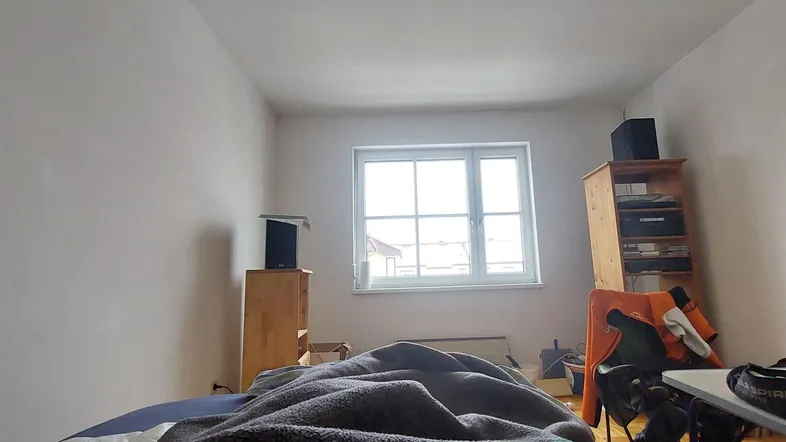 Helles Schlafzimmer mit Fenster und einfacher Einrichtung, bietet viel natürliches Licht.