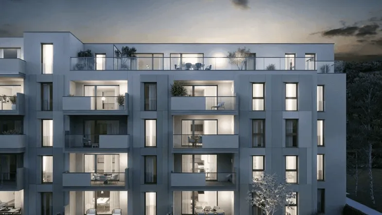 Moderne Wohnanlage bei Dämmerung mit beleuchteten Balkonen und Terrassen.