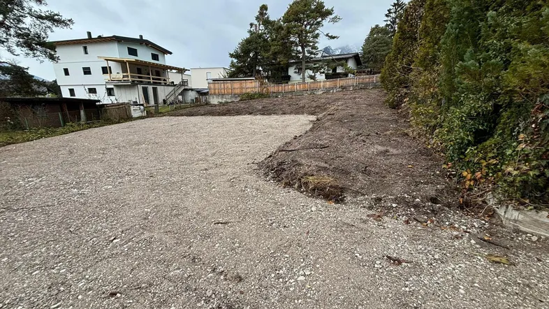 Großes Grundstück mit Schotterfläche und umliegender Vegetation, bereit für die Bebauung oder Nutzung als Parkplatz.