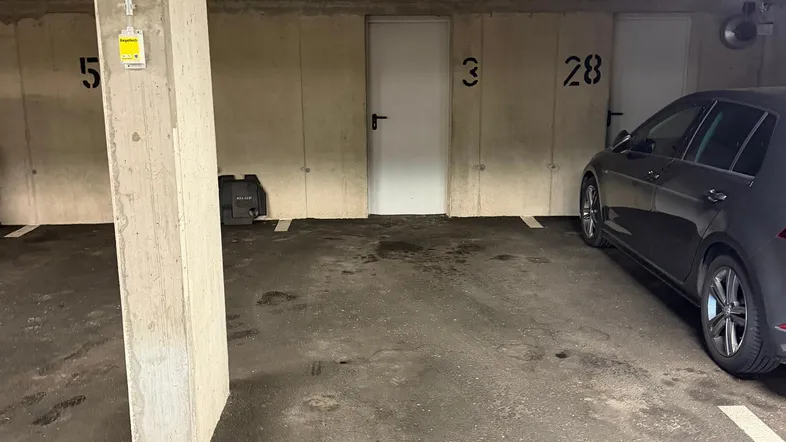 Saubere Tiefgarage mit Betonpfeilern und nummerierten Stellplätzen, ein Auto ist geparkt.