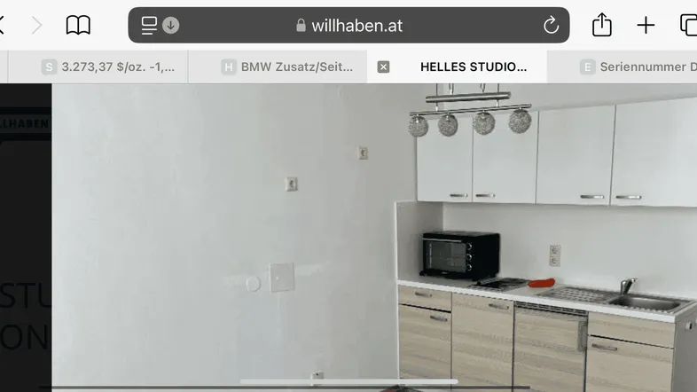 Helle Küchenzeile mit weißen Oberschränken und integrierter Mikrowelle in einem Studioapartment.