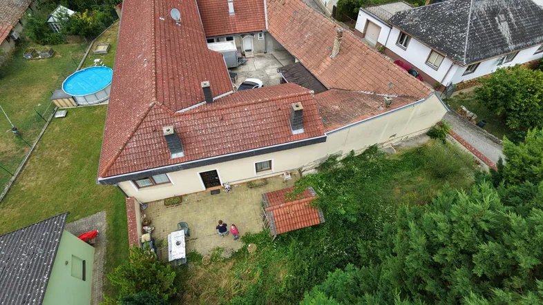 Luftaufnahme eines U-förmigen Anwesens mit Innenhof, Garten und kleinem Pool.