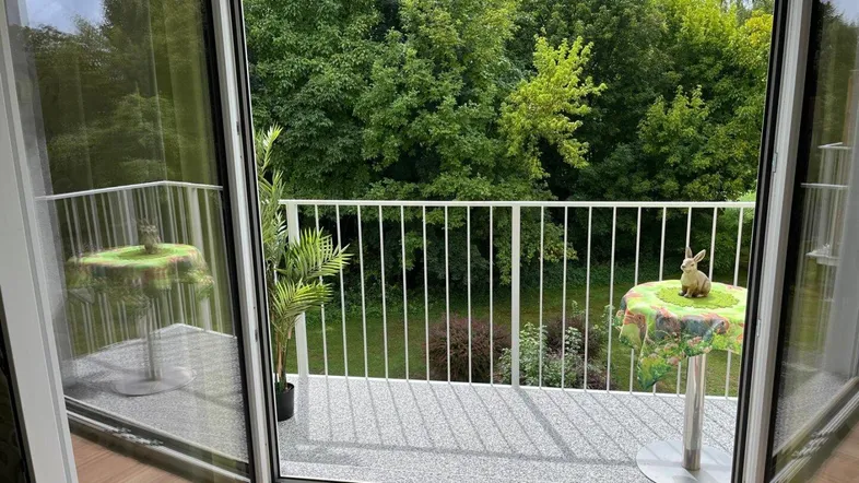 Balkon mit grüner Aussicht auf Bäume und Pflanzen, ideal zum Entspannen.