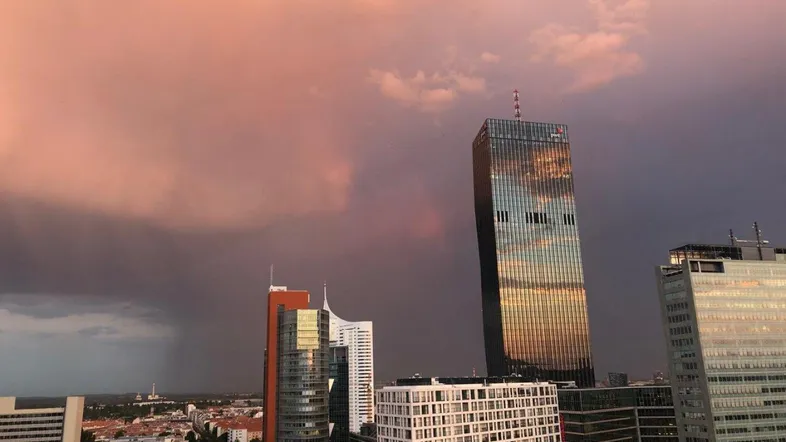 Stadtansicht mit modernen Wolkenkratzern unter einem dramatischen, bewölkten Abendhimmel.