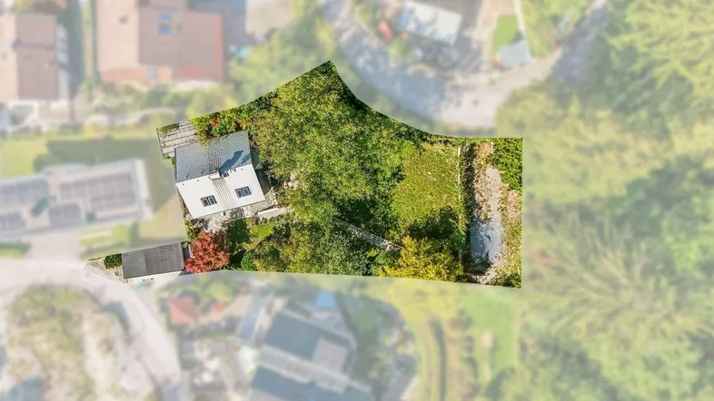 Luftaufnahme des Grundstücks mit Einfamilienhaus und großem Gartenbereich in grüner Umgebung.