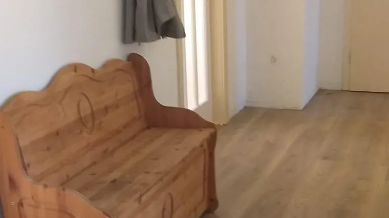 Heller Flur mit rustikaler Holzbank, Garderobe und Laminatboden, der einen einladenden Eingangsbereich schafft.