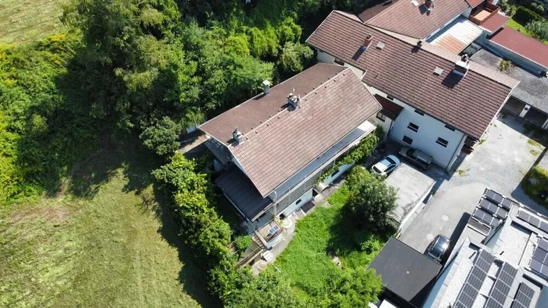 Luftaufnahme eines Hauses mit Satteldach, umgeben von viel Grün und einem Gartenbereich.