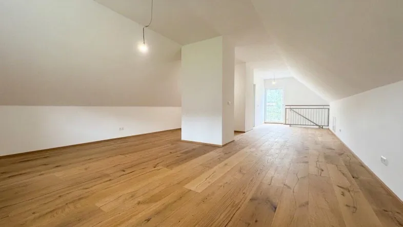 Geräumiger Dachbodenraum mit sichtbaren Dachschrägen und neuem Holzboden, bereit für den Ausbau.