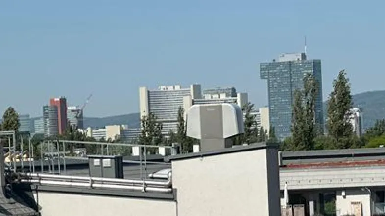 Panoramablick über die Stadt mit modernen Gebäuden und Bergkulisse im Hintergrund.